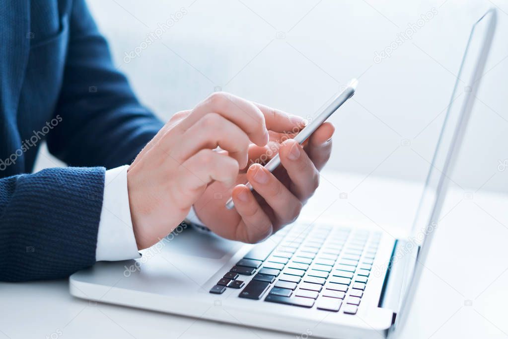 Businessman using laptop and phone