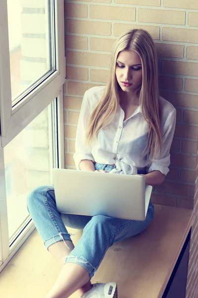 Mulher na janela usando laptop — Fotografia de Stock