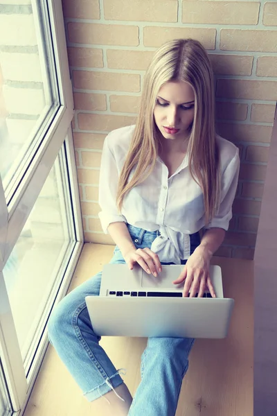 Mulher na janela usando laptop — Fotografia de Stock