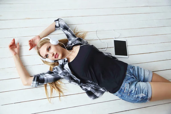 Woman in headphones lying on floor — Stock Photo, Image