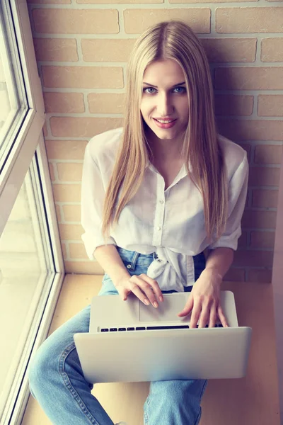 Vrouw aan het venster met behulp van laptop — Stockfoto