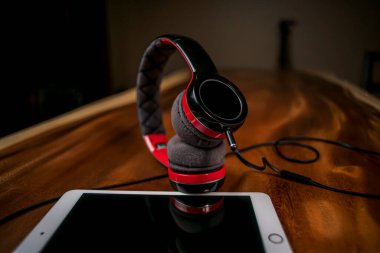 Modern kulaklığın ve tabletin siyah arka planı olan ahşap masadaki görüntüsünü kapat.