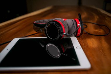 Kulaklığın ve tabletin ahşap masadaki görüntüsünü kapat