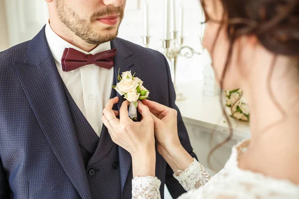 Noiva coloca noivo no boutonniere de rosa e whote rosa no dia do casamento — Fotografia de Stock