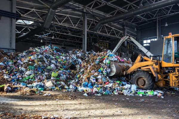 Grävmaskinen staplar skräp i stora högen vid sortering av moderna avfallsåtervinningsanläggningar. Separat och sortera sophämtning. Återvinning och lagring av avfall — Stockfoto