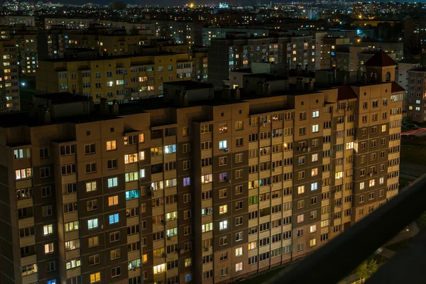 Panorama noturno da Luz nas janelas de um edifício de vários andares. vida em uma cidade grande — Fotografia de Stock