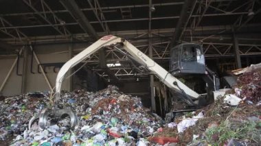 Grodno, Belarus - Ekim 2019: kazıcı modern atık geri dönüşüm tesisinde çöp yığını oluşturuyor. Çöp toplama ve ayıklama. Atıkların geri dönüşümü ve depolanması