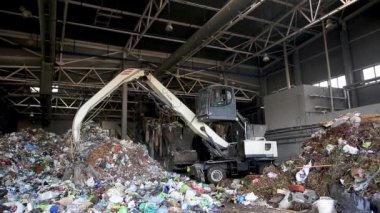 Grodno, Belarus - Ekim 2019: kazıcı modern atık geri dönüşüm tesisinde çöp yığını oluşturuyor. Çöp toplama ve ayıklama. Atıkların geri dönüşümü ve depolanması