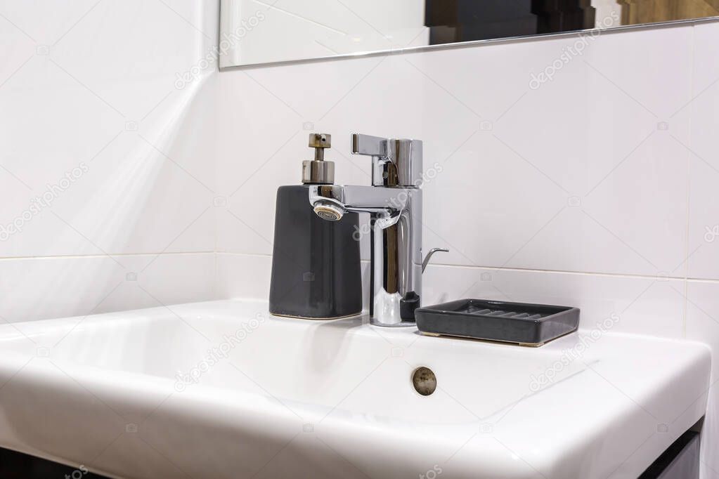 Soap and shampoo dispensers near Ceramic Water tap sink with fau