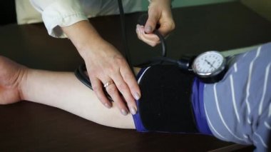 Kadın doktor hastada kan basıncını ölçer.