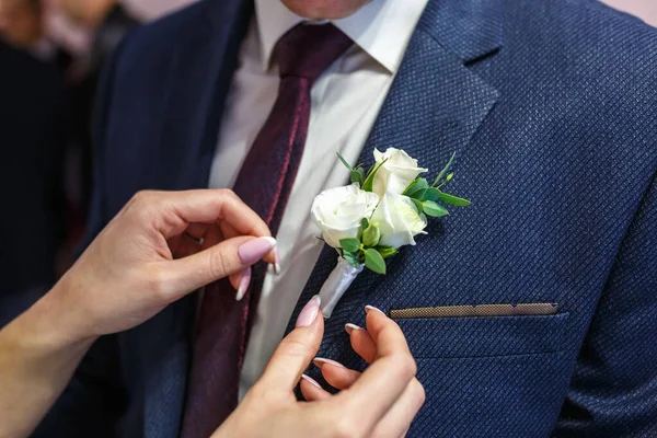 Невеста ставит жениха на бутоньерку из розового и Whote Rose в день свадьбы — стоковое фото