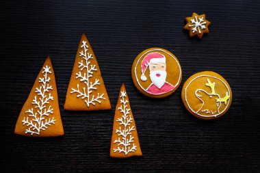 Yıldız şeklinde el yapımı şenlikli zencefilli kurabiye, kar taneleri, insanlar, çorap, personel, eldivenler, Noel ağaçları, xmas ve siyah ahşap arka plan üzerinde yeni yıl tatili için kalpler