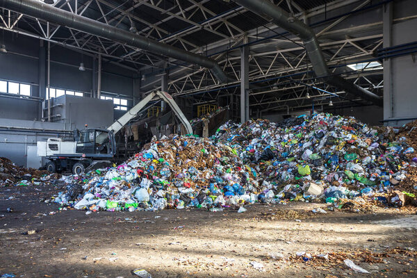 excavator stacks trash in big pile at sorting modern waste recyc
