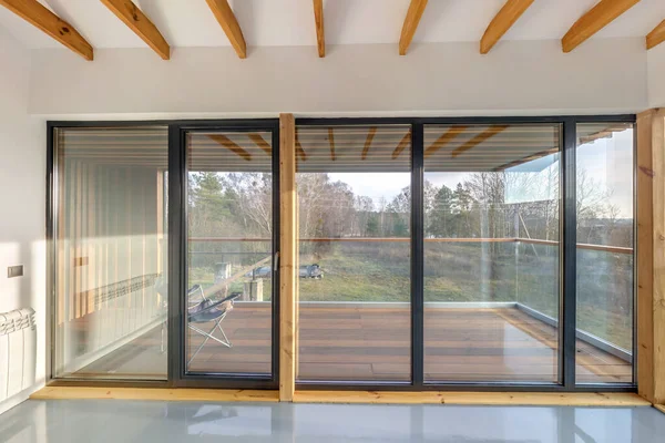 Белый пустой интерьер квартиры с панорамными окнами и деревянным потолком в дачном доме, с видом на природу в лесу — стоковое фото