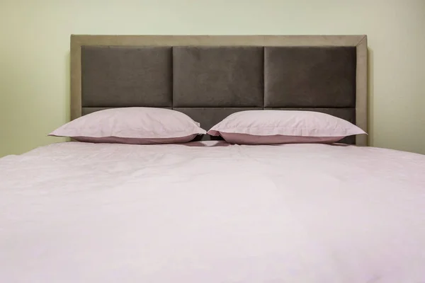Cama doble con almohadas en el interior del dormitorio íntimo moderno en loft piso en apartamentos de estilo de color claro —  Fotos de Stock