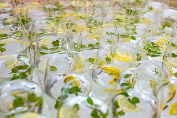 Banyak gelas kabur dengan koktail dengan lemon dan mint di meja resepsionis — Stok Foto