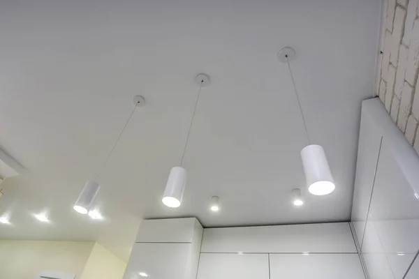 Halojen benekli lambalar asılmış tavanda ve alçıpan inşaatında boş bir odada ya da evde. Gergin tavan beyaz ve karmaşık şekil. — Stok fotoğraf