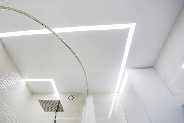 Halogen spots lamps on suspended ceiling and drywall construction in in empty room in apartment or house. Stretch ceiling white and complex shape. — Stock Photo, Image