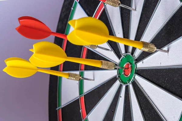 Red and yellow dart arrows hitting in the target center of dartb — Stock Photo, Image
