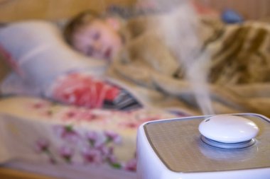 steam flow from a humidifier and an air ionizer in a blurred room with a sleep small child. Climatic device used to increase indoor humidity. respiratory disease prevention clipart