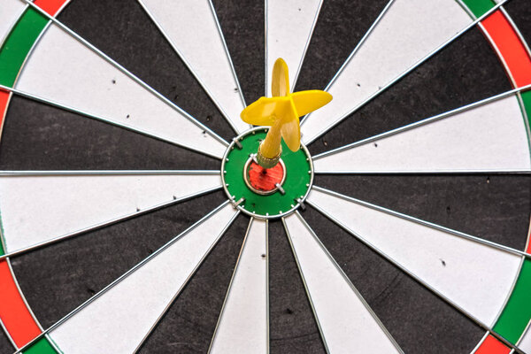 Red and yellow dart arrows hitting in the target center of dartb