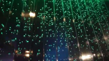 Suyun içindeki renkli hava kabarcıkları şeffaf duvarda gece kulübünde ya da kumarhanede yeşil ışıkta.