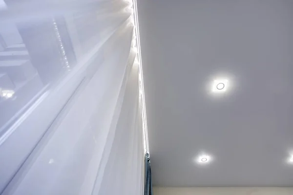 Галогенні плями світильників на підвісній стелі і гіпсокартоні в порожній кімнаті в квартирі або будинку. Натяжна стеля біла і складна форма . — стокове фото