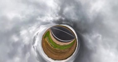 Uzayın kıvrımlı küçük bir gezegen dönüşümü. Fırtınadan önce bulutlu bir günde tarlalar arasında aspahlt yolunda tam uçuş panoramasının soyut dönüş, bükülme ve dönüşü.
