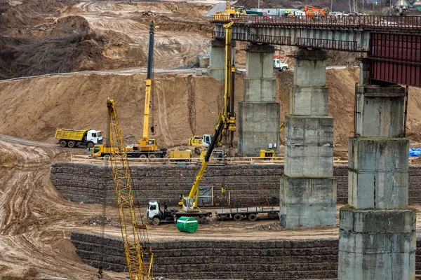 Construction or reconstruction of highway concrete bridge over a wide river. construction machinery, trucks and cranes work — Stockfoto