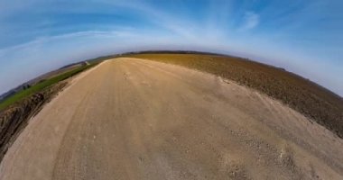 Little planet Transformation with curvature of space. Abstract rotate, torsion and spinning of full flyby panorama on asphalt road among fields in sunny day with clear sky