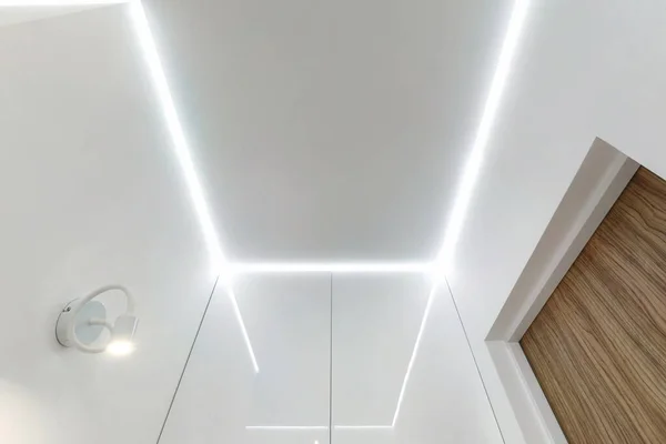 suspended ceiling with halogen spots lamps and drywall construction in empty room in apartment or house. Stretch ceiling white and complex shape.