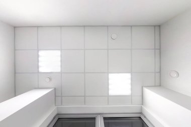 kaset asılmış tavanda kare halojen benekli lambalar ve boş bir oda ya da evde alçıpan inşaatı. Gergin tavan beyaz ve karmaşık şekil. Manzaraya bakıyorum