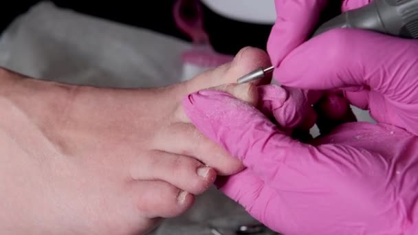 粉红手套的教育家大师是用钻头在修脚沙龙里切割角质层和果胶趾钉的人 美容外科诊所的专业修脚 美容院的脚卫生 — 图库视频影像