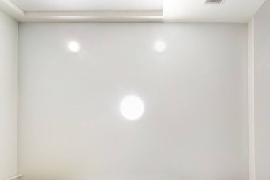 Boş bir odada, dairede ya da evde lambalar ve alçıpan döşemeli asılmış tavan. Gergin tavan beyaz ve karmaşık şekil. Yukarı bakıyorum.