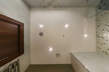 Halojen benekli lambalar ve alçıpan inşaatı ile asılı tavana bak. Daire ya da evdeki boş odada yangın alarmı sensörü var. Gergin tavan beyaz ve karmaşık şekil.