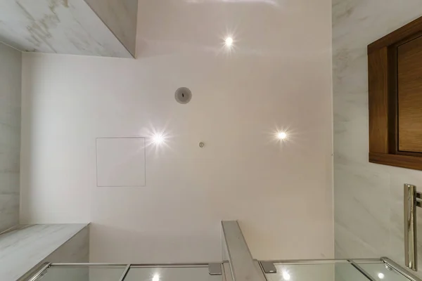 ハロゲンスポットランプ付きの吊り下げ天井を見上げ アパートや家の中の空の部屋に火災警報センサー付きの乾式壁の建設 天井の白と複雑な形状をストレッチ — ストック写真