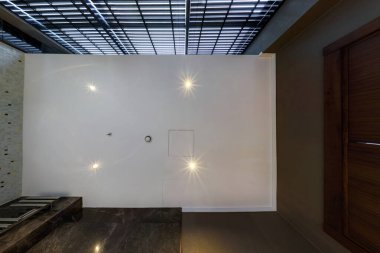 Halojen benekli lambalar ve alçıpan inşaatı ile asılı tavana bak. Daire ya da evdeki boş odada yangın alarmı sensörü var. Gergin tavan beyaz ve karmaşık şekil.