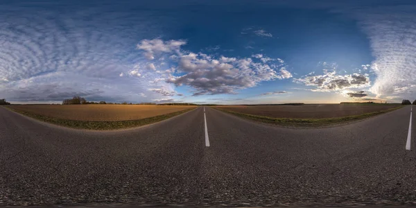 Full spherical seamless panorama 360 degrees angle view on no traffic asphalt road among fields in evening  before sunset with cloudy sky. 360 panorama in equirectangular projection, VR AR content