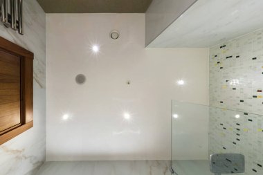 Halojen benekli lambalar ve alçıpan inşaatı ile asılı tavana bak. Daire ya da evdeki boş odada yangın alarmı sensörü var. Gergin tavan