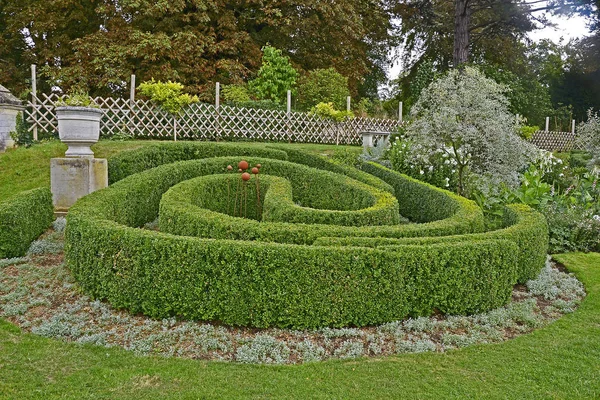 A large garden border with circular topiary hedge in a country house garden