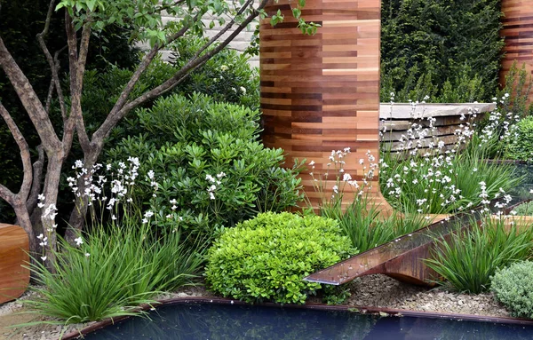 Lato piscina di un giardino urbano con albero, posti a sedere e fiori bianchi — Foto Stock