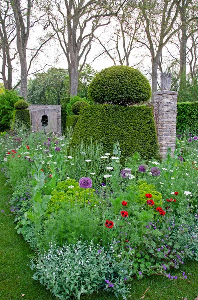 花边一种五彩缤纷的混合花边 位于一个有装饰石雕装饰的正规花园中 — 图库照片