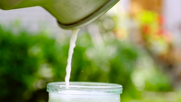 Pouring milk into the glass jar. Close up — Stock Video