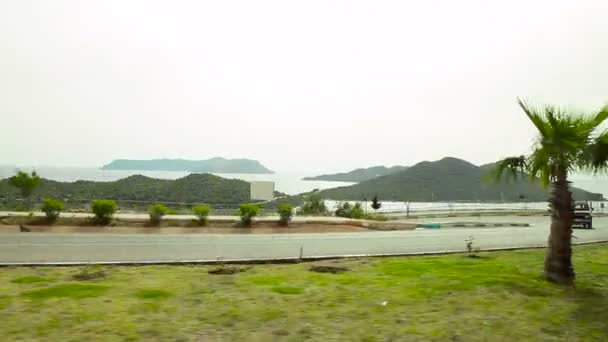 Widok z boku z samochodu z morzem i górami w tle. — Wideo stockowe