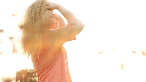 Красива дівчина з кучерявим волоссям позує на камеру. Зйомки повільного руху. Захід сонця — стокове відео