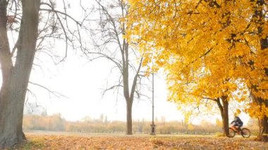 A man rides a bicycle in the park. Yellow autumn trees. Fallen leaves on the ground. Slow motion10.15.2019 Ukraine. Kiev VDNH