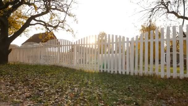 City park in the fall. White wooden fence. Bright rays of the sun — Stockvideo