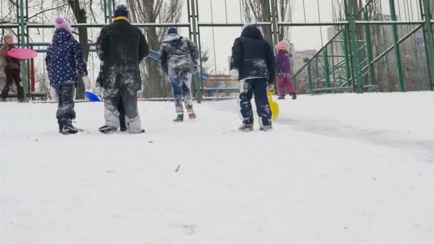 Guys climb up a snowy hill. Slow motion. Winter holidays for children 10.01.2020 Ukraine, Kiev — Wideo stockowe