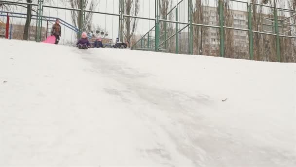Den lille jenta kommer ned fra en snødekt bakke. Slow motion 01.10.2020 Ukraina, Kiev – stockvideo