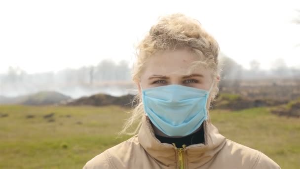 Vacker flicka i medicinsk mask. Rökfält. Sakta i backarna. Närbild — Stockvideo